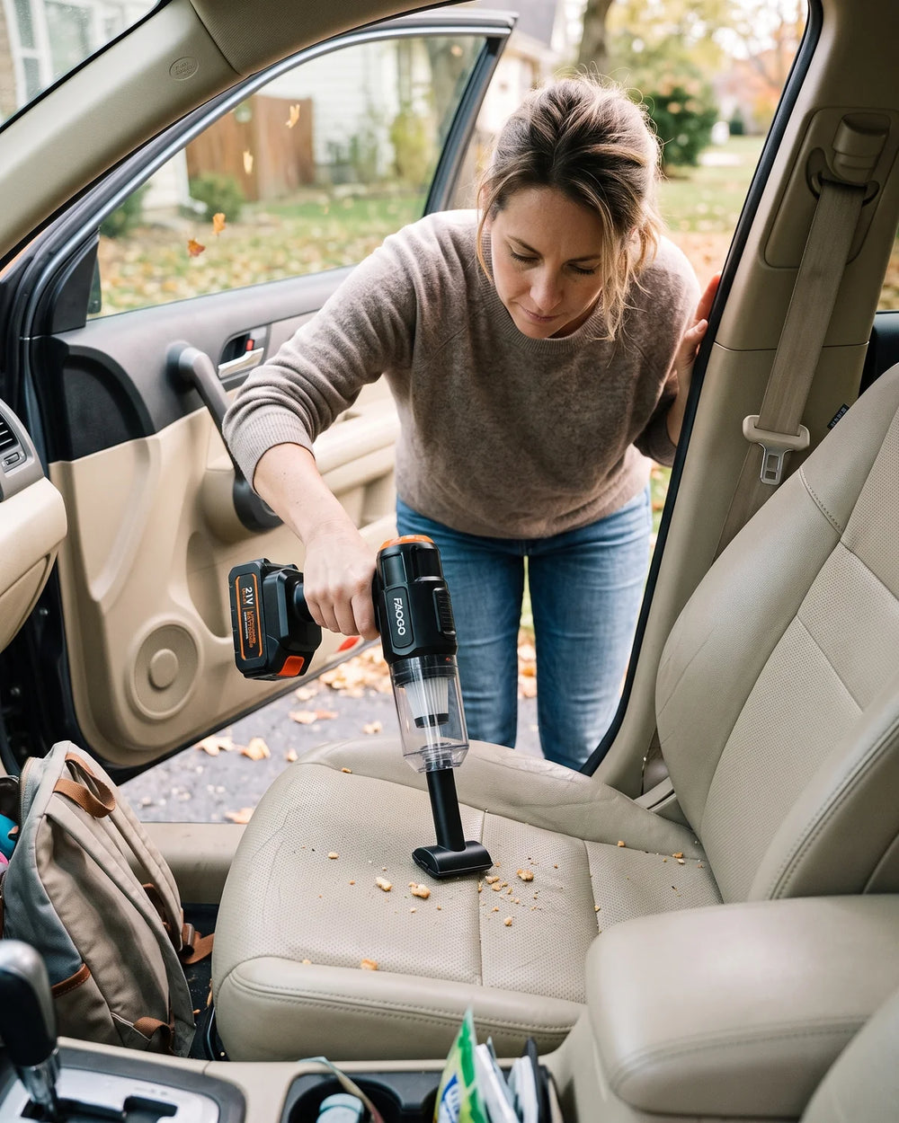 Woman using a FAOGO car vacuum to clean crumbs from a light-colored car seat