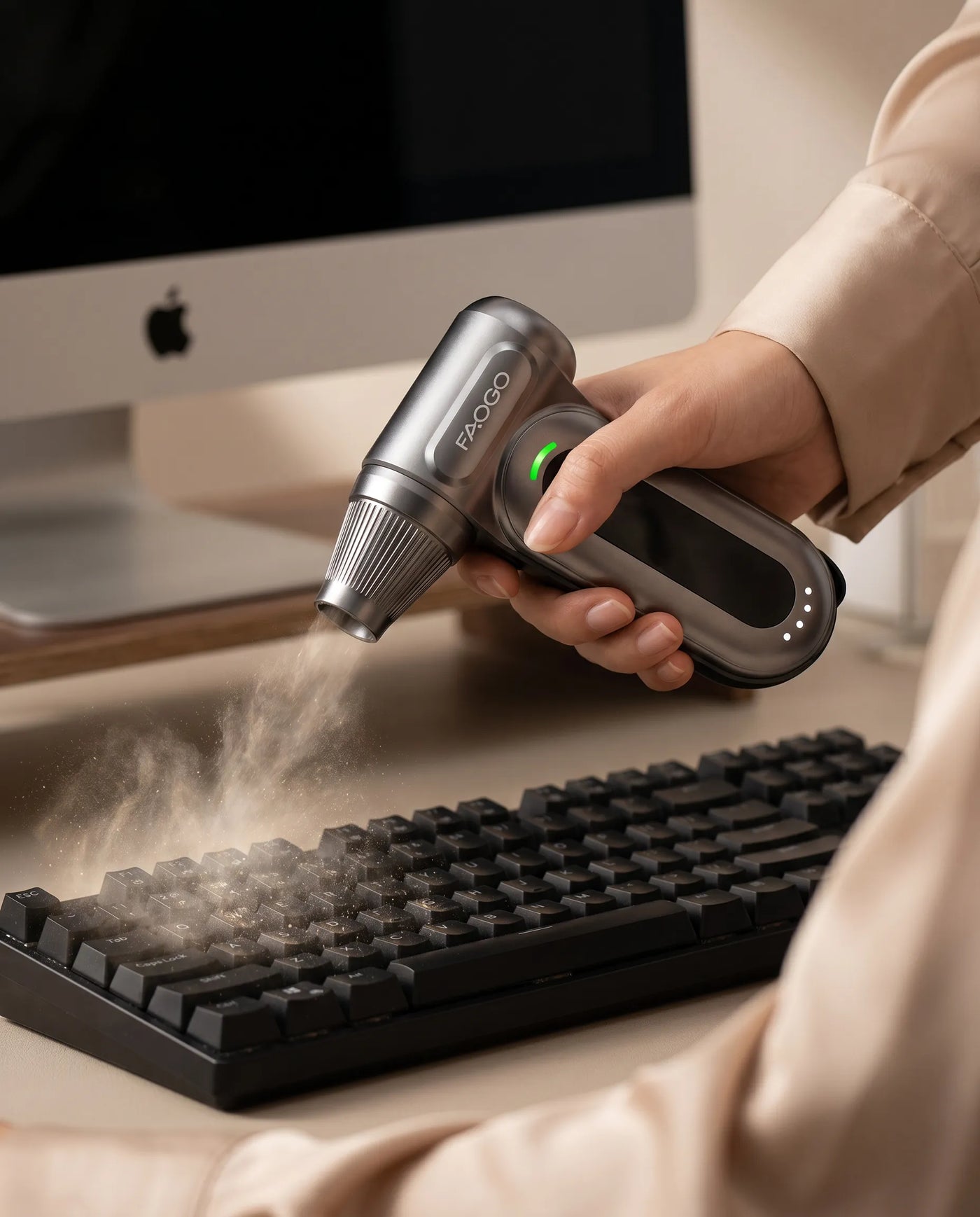 FAOGO reusable electronic duster blowing dust from a mechanical keyboard. Cordless mini desk cleaner for office tech setups.